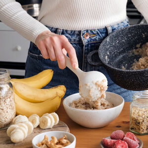 Close up of putting cereal into a bowl next to bananas