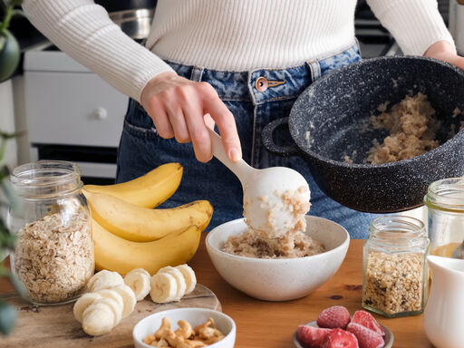 Close up of putting cereal into a bowl next to bananas