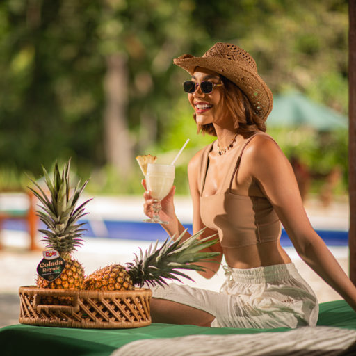 Women drinking a cocktail with Colado Royale Pineapples near her in a basker