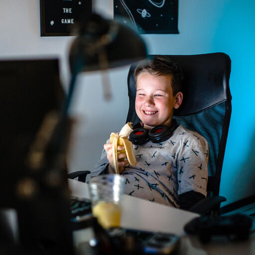 Boy infront of a computer eating banana